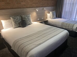 A hotel room with two beds, each with patterned bedding and pillows. - Hamilton's Henry Parkes Motor Inn, Parkes (Parkes)