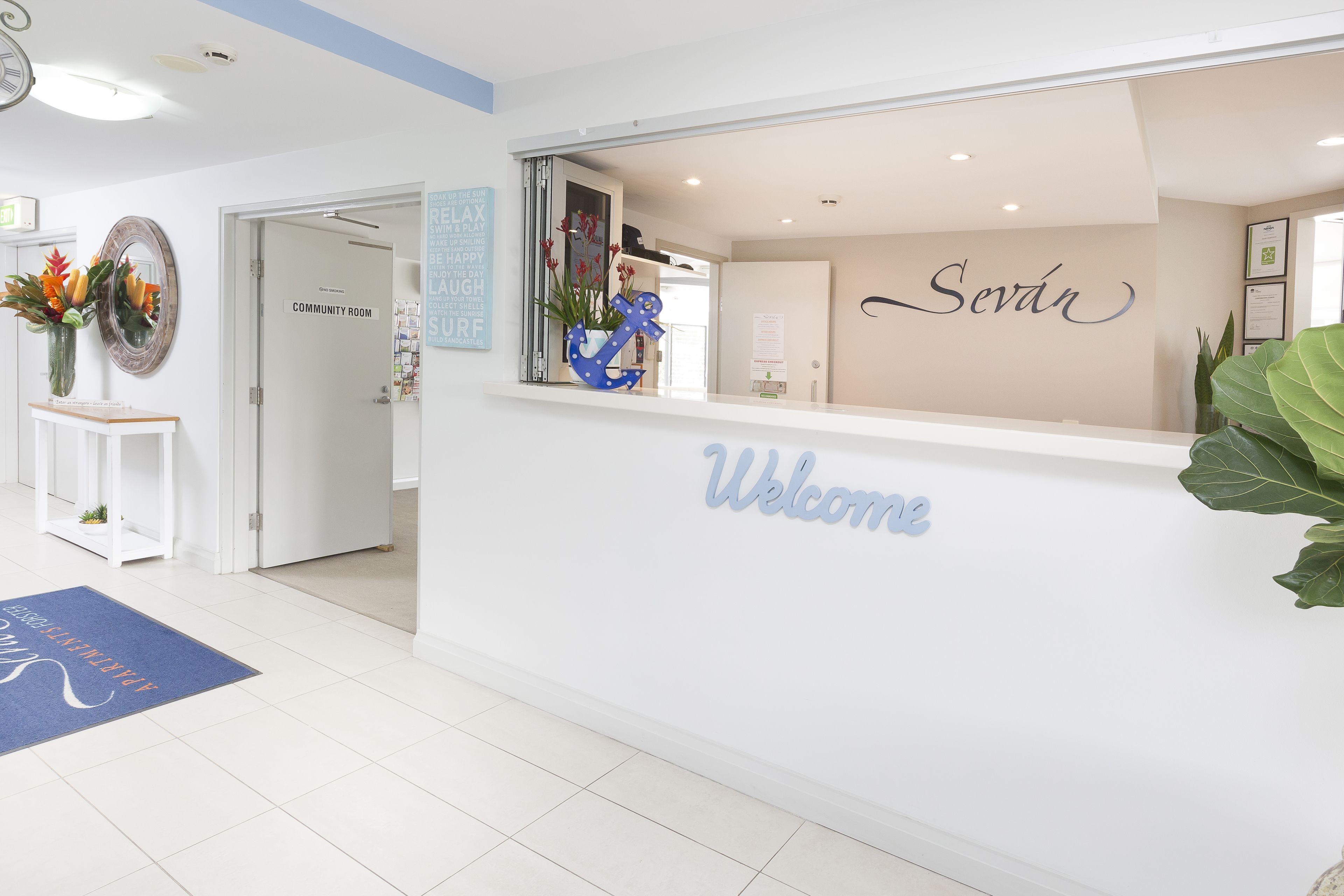 Un espace d’accueil avec une pancarte « Bienvenue », une autre indiquant « Salle communautaire », et une ancre décorative accrochée au mur.