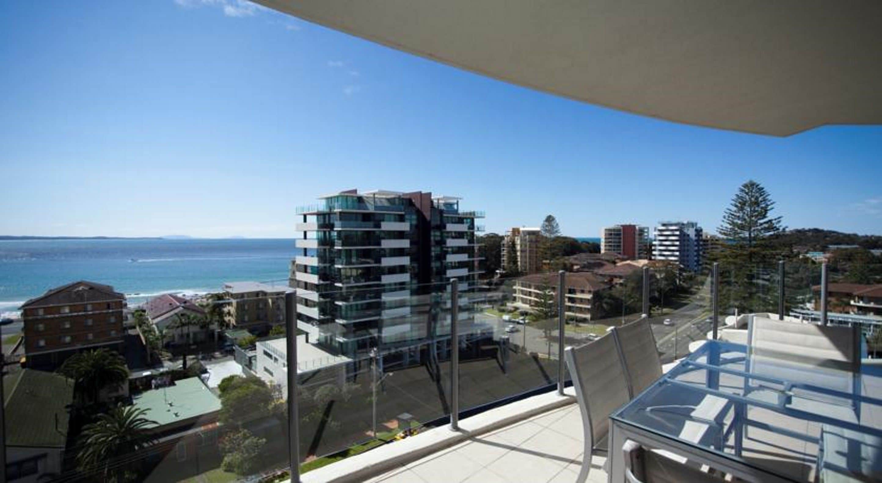 A modern building with a glass facade overlooking a coastal area.