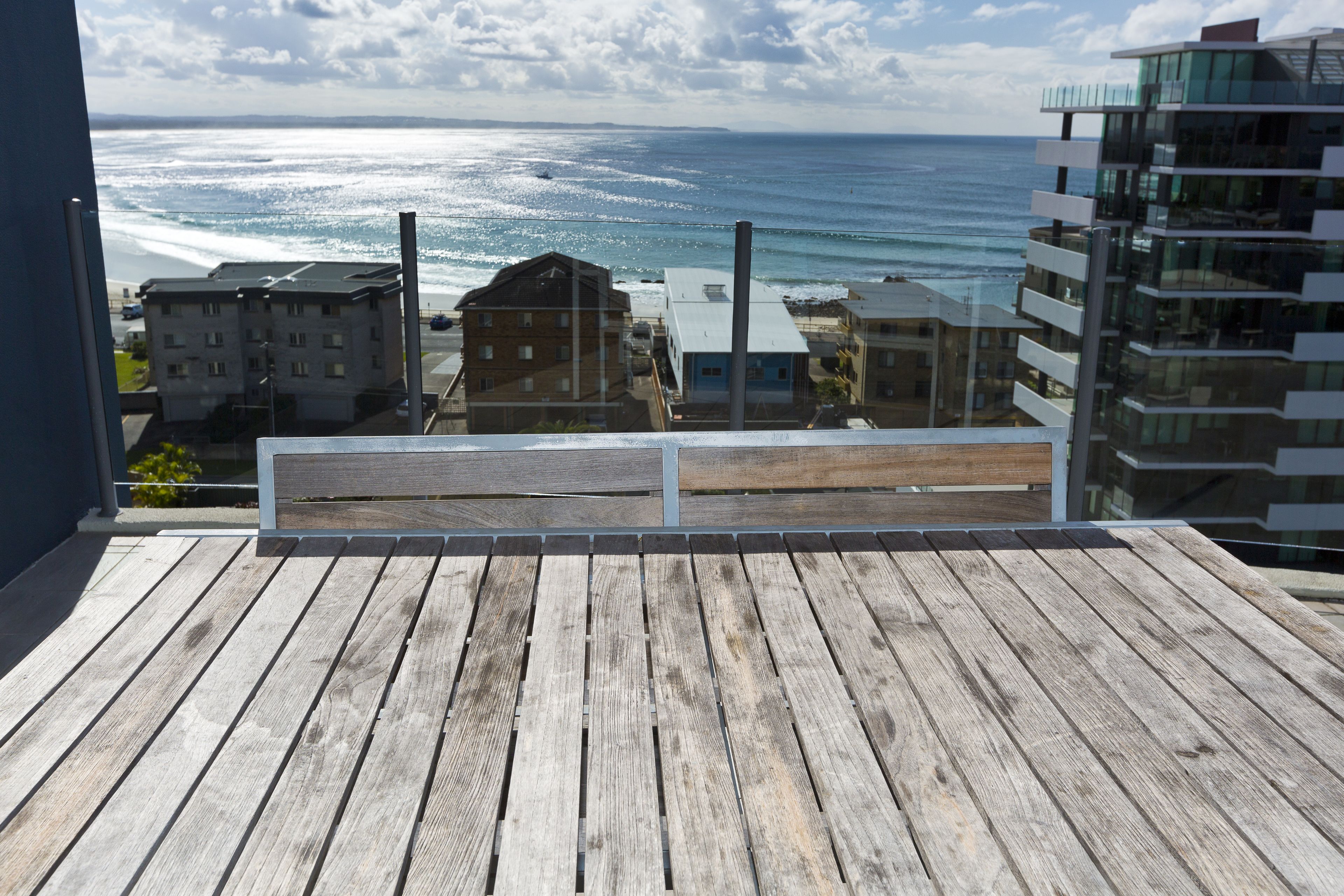 A wooden deck with a view of the ocean and buildings in the background.