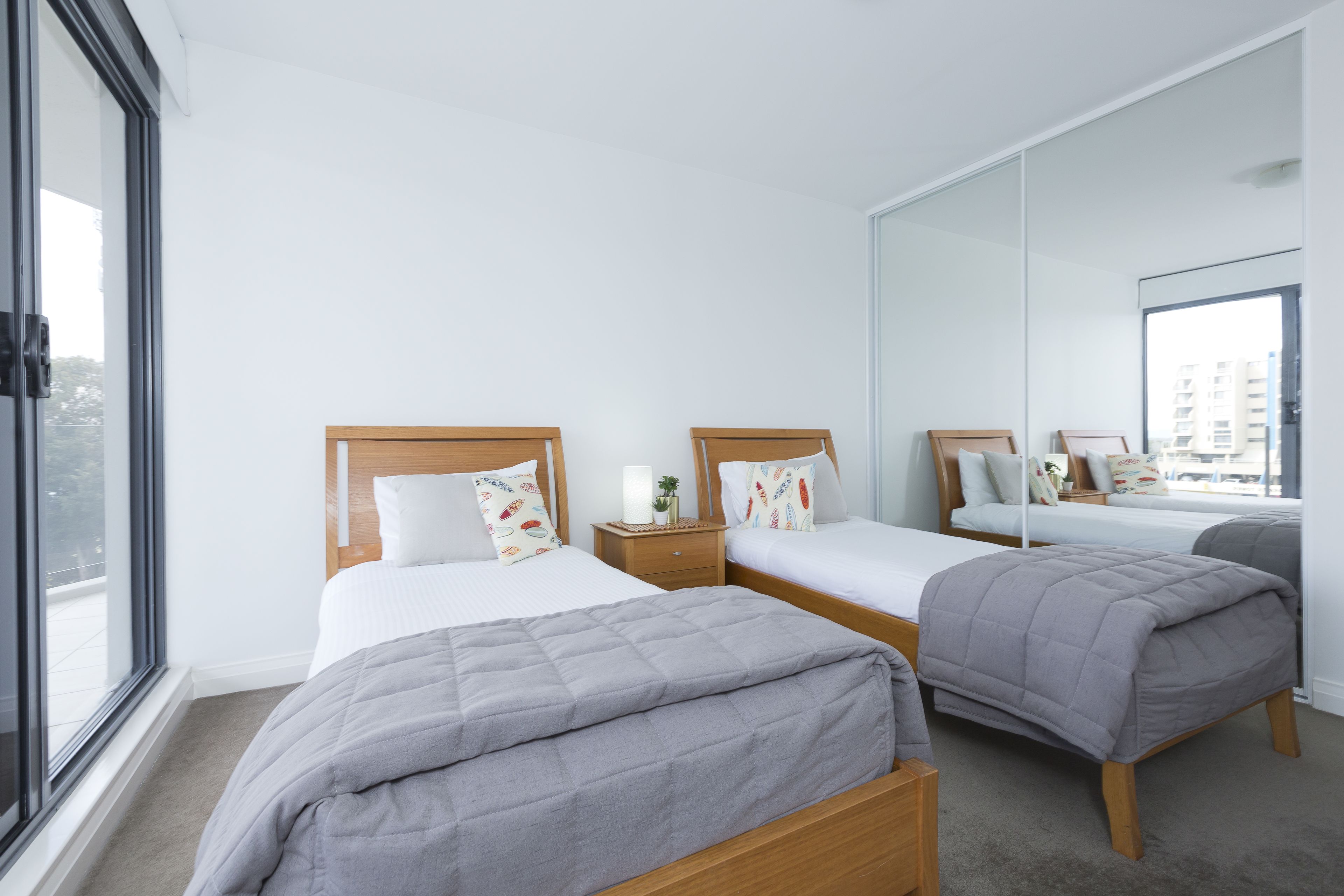 A hotel room with two beds, a large mirror, and a view of the city.