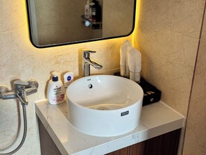 A bathroom with a white ceramic sink, a mirror with a black frame, and toiletries on the counter. - A25 Hotel - Doi Can 2 (Hanoi)