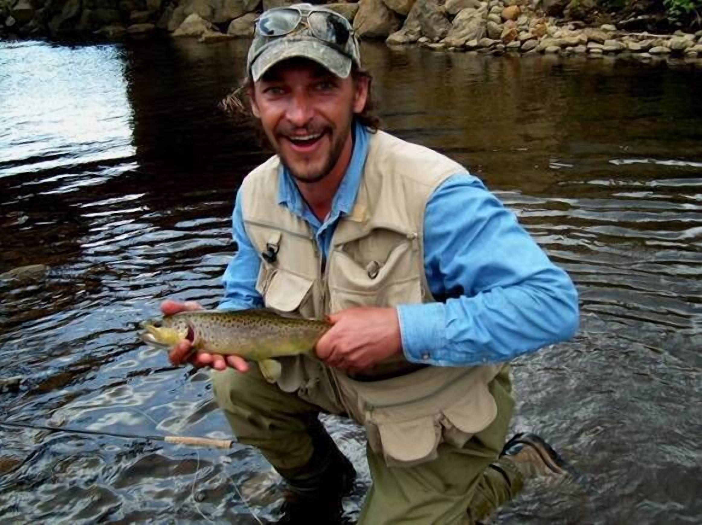 Una persona sosteniendo un pez en un río.