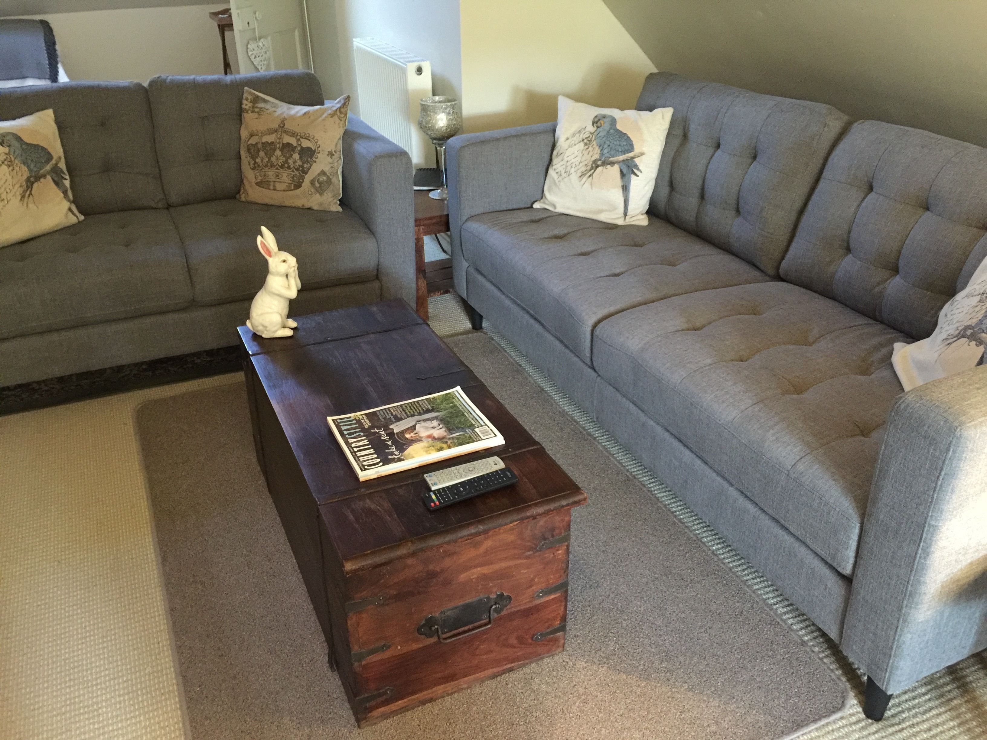 A living room with a grey sofa, a small wooden coffee table, and a decorative rabbit statue.