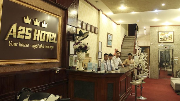 A reception area with a sign reading "A25 HOTEL" and a counter with staff.