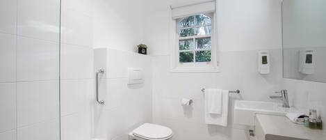 Ein modernes Badezimmer mit Badewanne, Toilette, Waschbecken und einem Fenster.