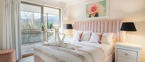 Une chambre à coucher avec un grand lit, deux tables de chevet, une commode, une fenêtre avec des rideaux et un tableau au mur.