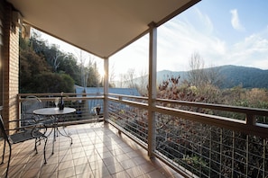 Enjoy the serene views of the surrounding landscape from this balcony with a table and two chairs.