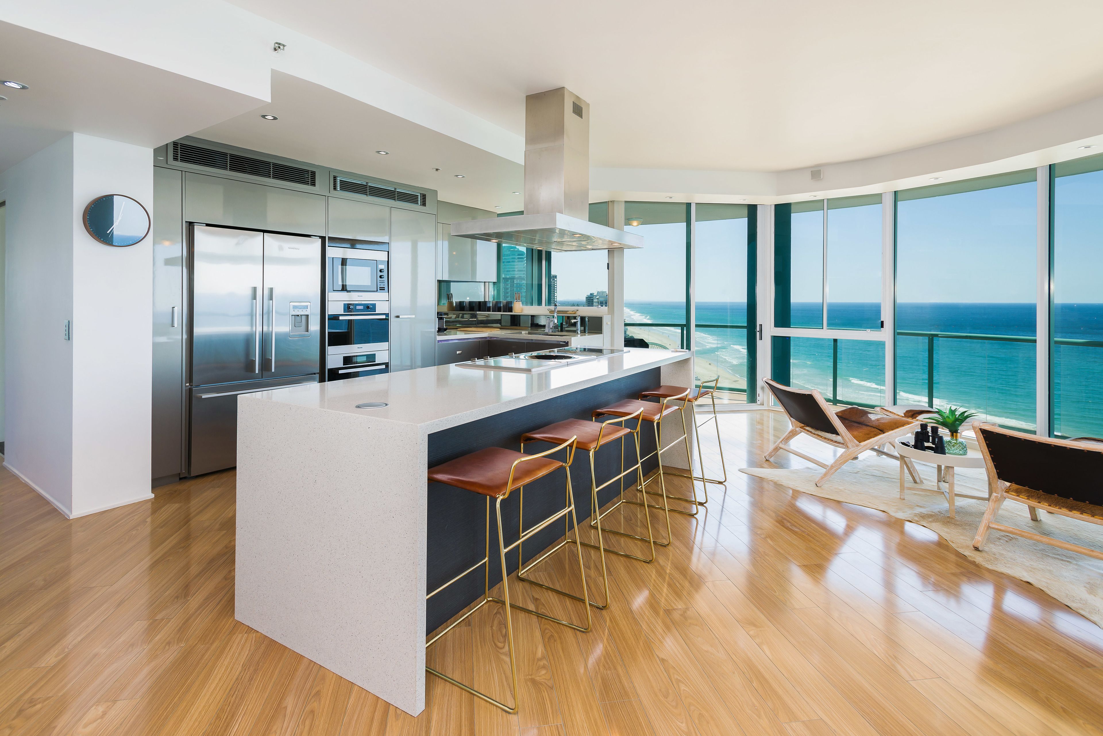 Una cocina moderna con una isla grande, electrodomésticos de acero inoxidable y vista al océano.