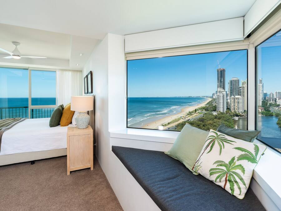 Ein Schlafzimmer mit großem Fenster und Blick auf Stadt und Strand.