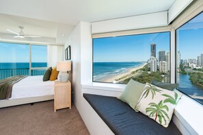 Ein Schlafzimmer mit großem Fenster und Blick auf Stadt und Strand.