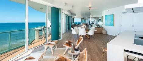 Un interior espacioso con un balcón grande con vistas al océano, muebles modernos y una zona de cocina.