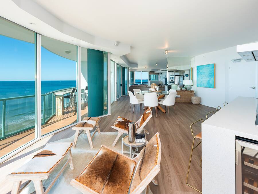 Un interior espacioso con un balcón grande con vistas al océano, muebles modernos y una zona de cocina.