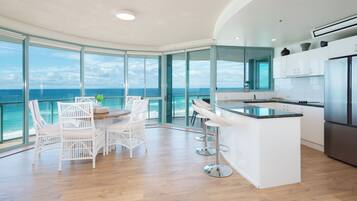 A modern kitchen with a large island, white cabinetry, and a view of the ocean.