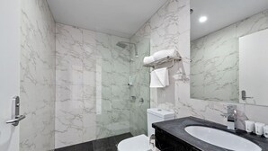 A modern bathroom with a glass-enclosed shower, a white toilet, and a black marble sink. - Areca Launceston (Launceston)