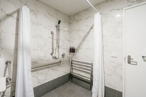 A bathroom with a shower, grab bars, a towel rack, and a door. - Areca Launceston (Launceston)