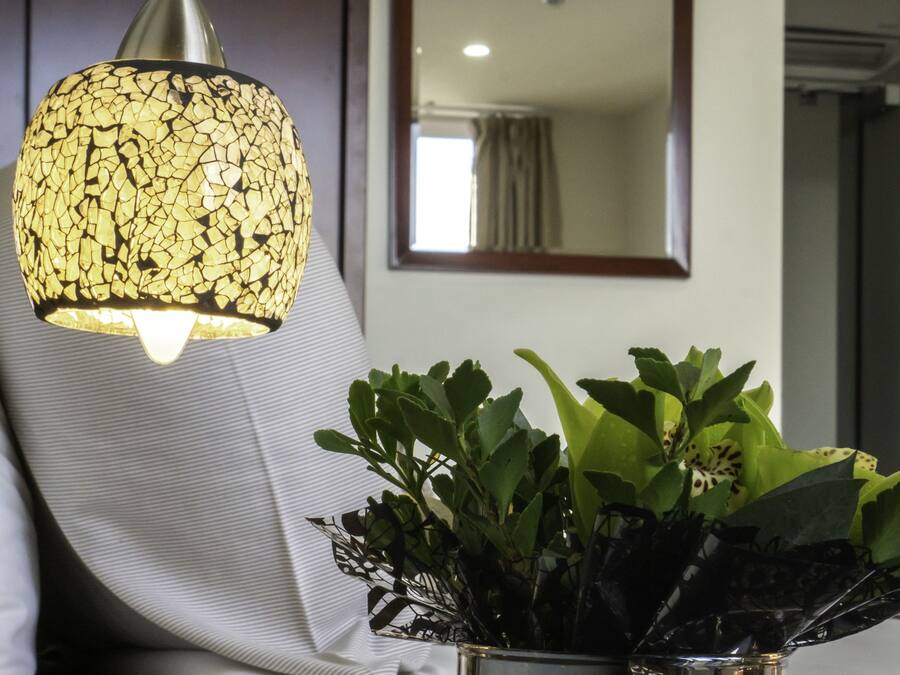 Ein modernes Zimmer mit einer strukturierten Lampe, einem Topfpflanzen und einem Spiegel an der Wand.