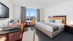 A hotel room with a large bed, a desk with a chair, a television, and a view of the outdoors. - Areca Launceston (Launceston)
