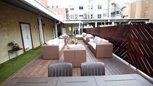 Une terrasse sur le toit dotée de plusieurs espaces de détente, notamment des canapés et des fauteuils, ainsi qu’une petite table.