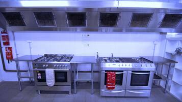 Una cocina industrial con dos estufas y hornos de acero inoxidable, y un extintor.