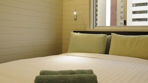 Une chambre d’hôtel avec un lit, une fenêtre avec des stores et une poutre en bois au plafond.