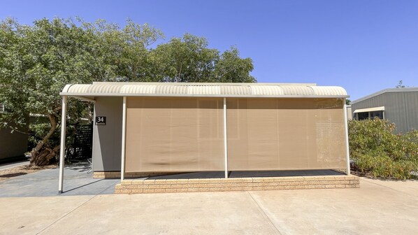 A covered outdoor seating area with a brick base, a metal roof, and a number sign indicating its location. - Capricorn Holiday Park (Brown Range)