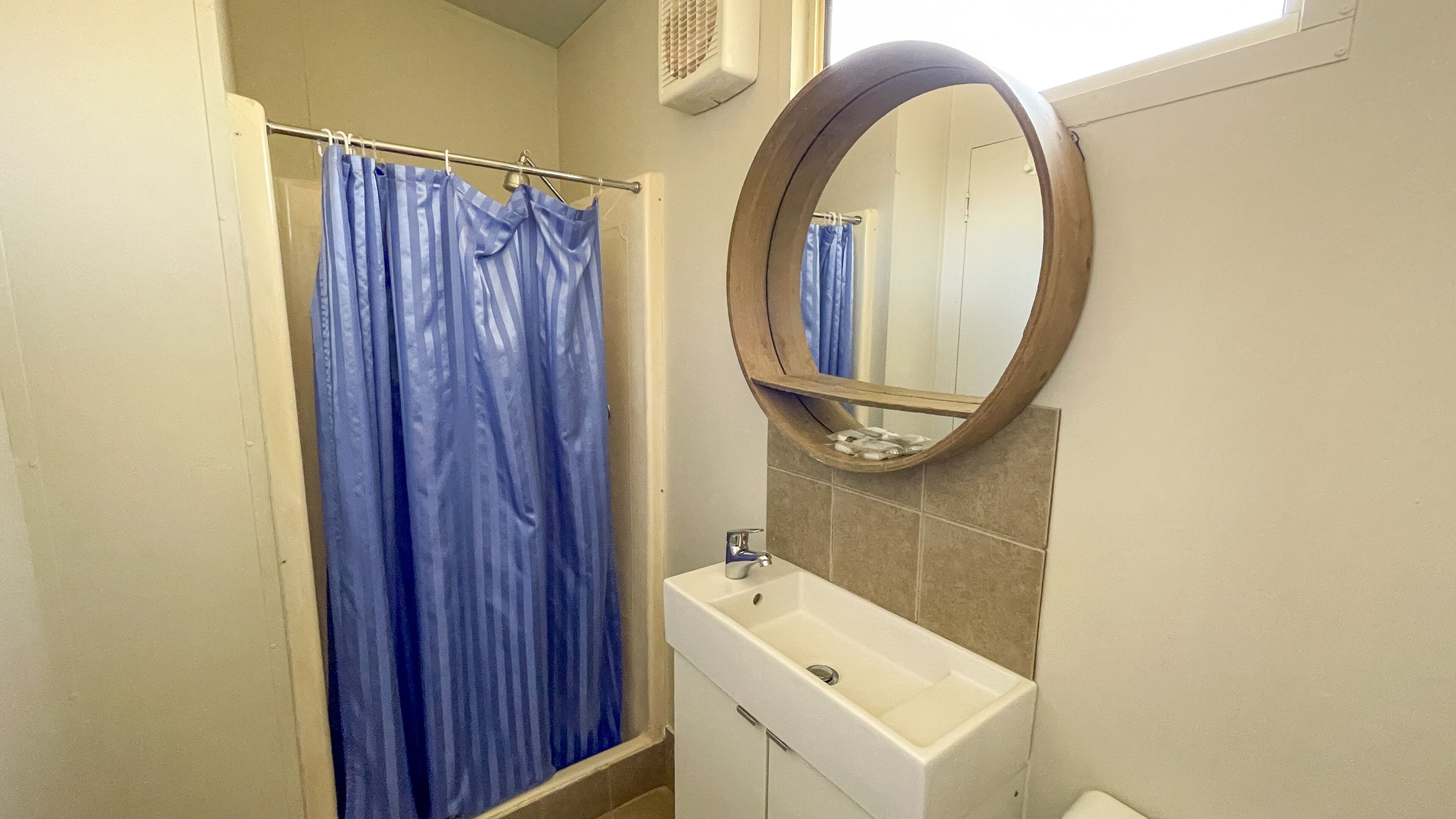 Une salle de bain avec un rideau de douche, un lavabo et un miroir.