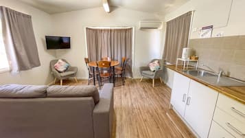 A compact living space with a sofa, dining table, chairs, a TV, and a kitchenette.