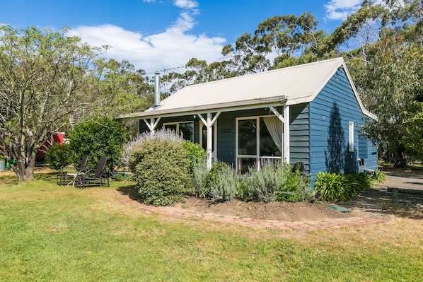 A blue house with a white roof, surrounded by greenery and trees.