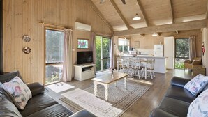 A spacious living area with a wooden ceiling, a dining table, and a kitchen in the background. - Freshwater Creek Cottages and Farm Stay (Freshwater Creek)