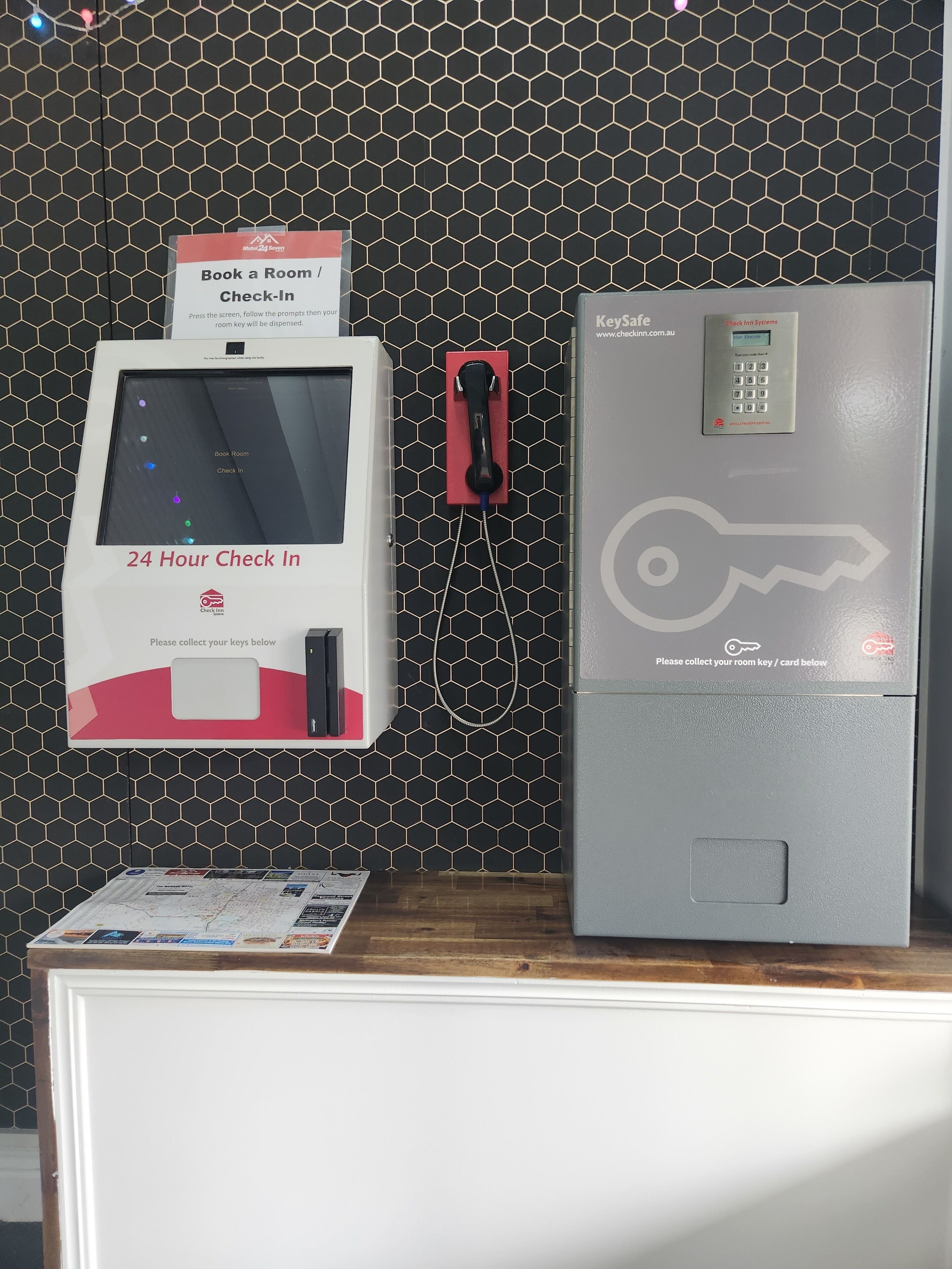 A hotel reception area with a check-in kiosk, a room key card dispenser, and a digital keycard reader.