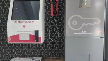 A hotel reception area with a check-in kiosk, a room key card dispenser, and a digital keycard reader.