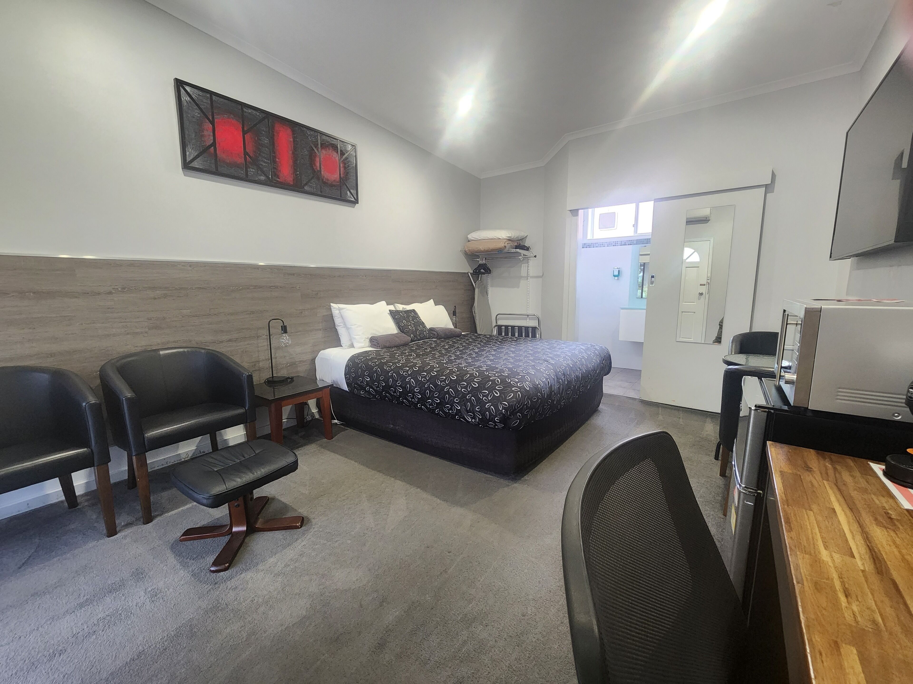 Une chambre d’hôtel moderne avec un grand lit, un bureau, deux chaises, une petite table et un téléviseur.