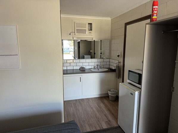 A compact kitchen with a refrigerator, microwave, and sink.
