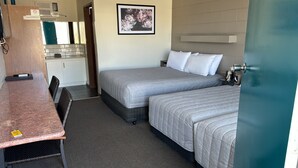 Habitación de hotel con dos camas, un escritorio, una silla, un baño y un cuadro en la pared.