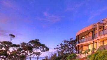 A modern hotel with a curved facade, large windows, and a landscaped garden.