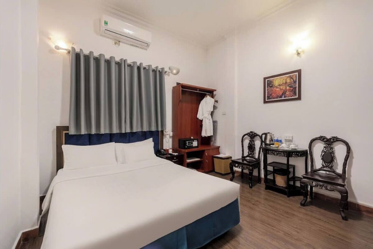 Habitació d'hotel amb un llit, un armari, escriptori, dues cadires i un quadre a la paret.