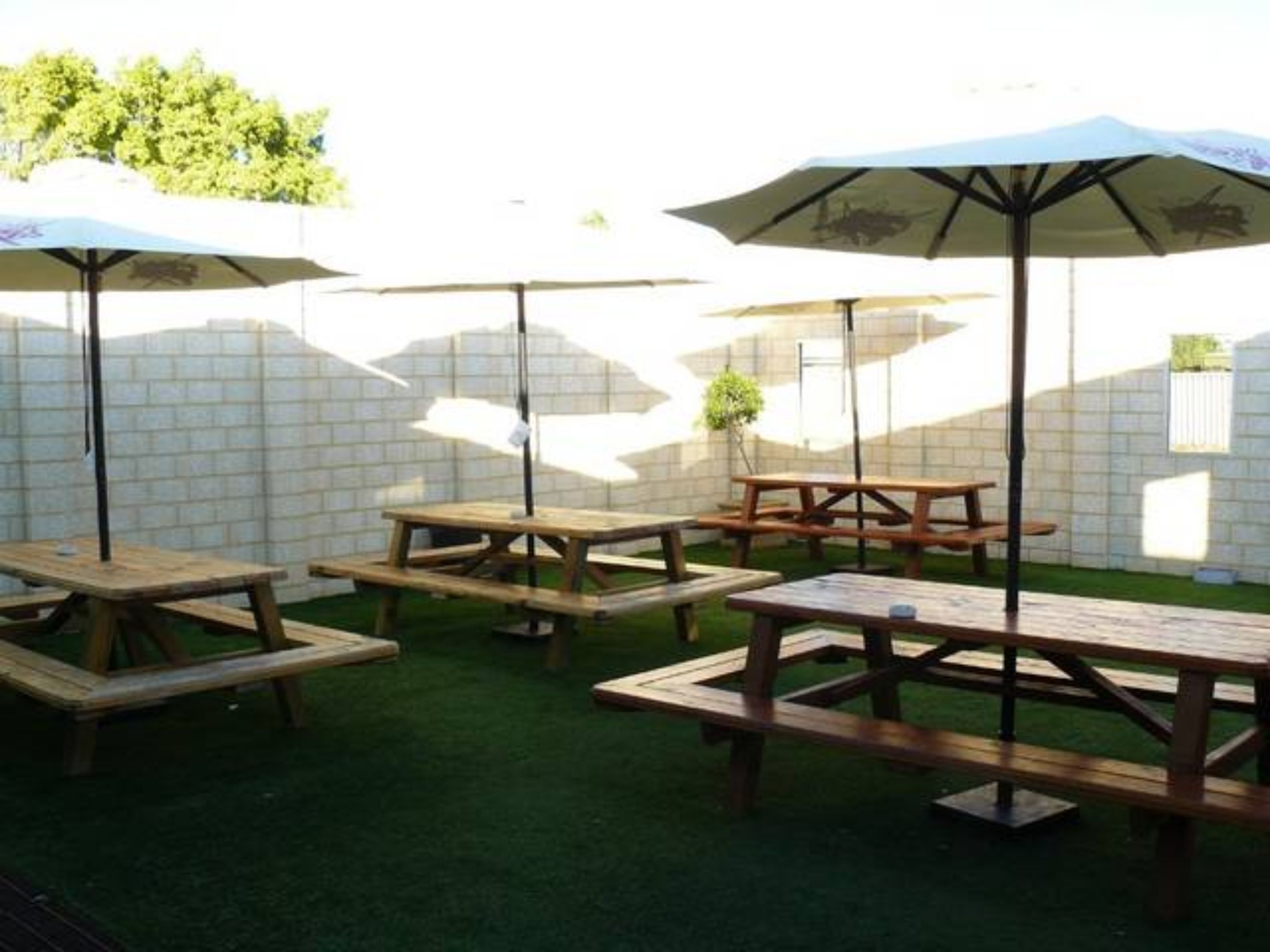 An outdoor patio area with wooden picnic tables and umbrellas.