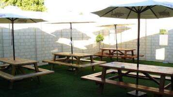 An outdoor patio area with wooden picnic tables and umbrellas.