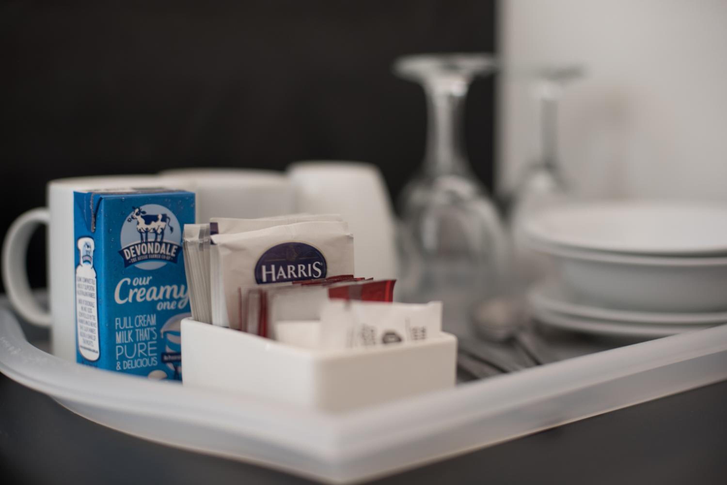 A tray with a carton of Devondale milk, a Harris milk carton, and a glass of milk.