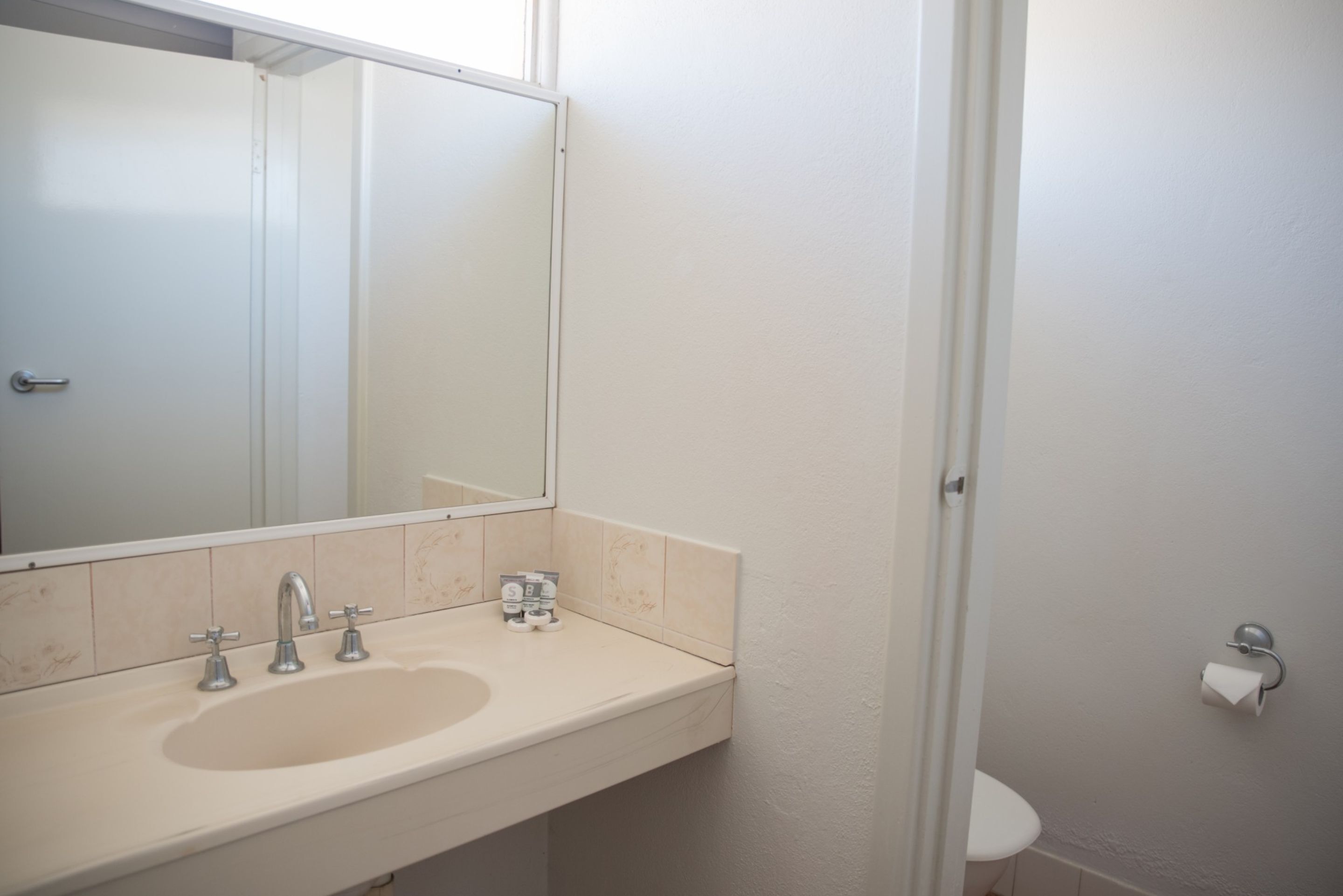 A bathroom with a sink, mirror, and toilet.