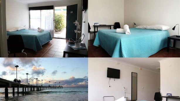 Une chambre d’hôtel avec deux lits, un bureau, une chaise, une télévision et une vue sur la plage et la jetée.