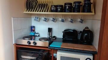 A compact kitchen with a toaster oven, a microwave, a kettle, and a toaster.