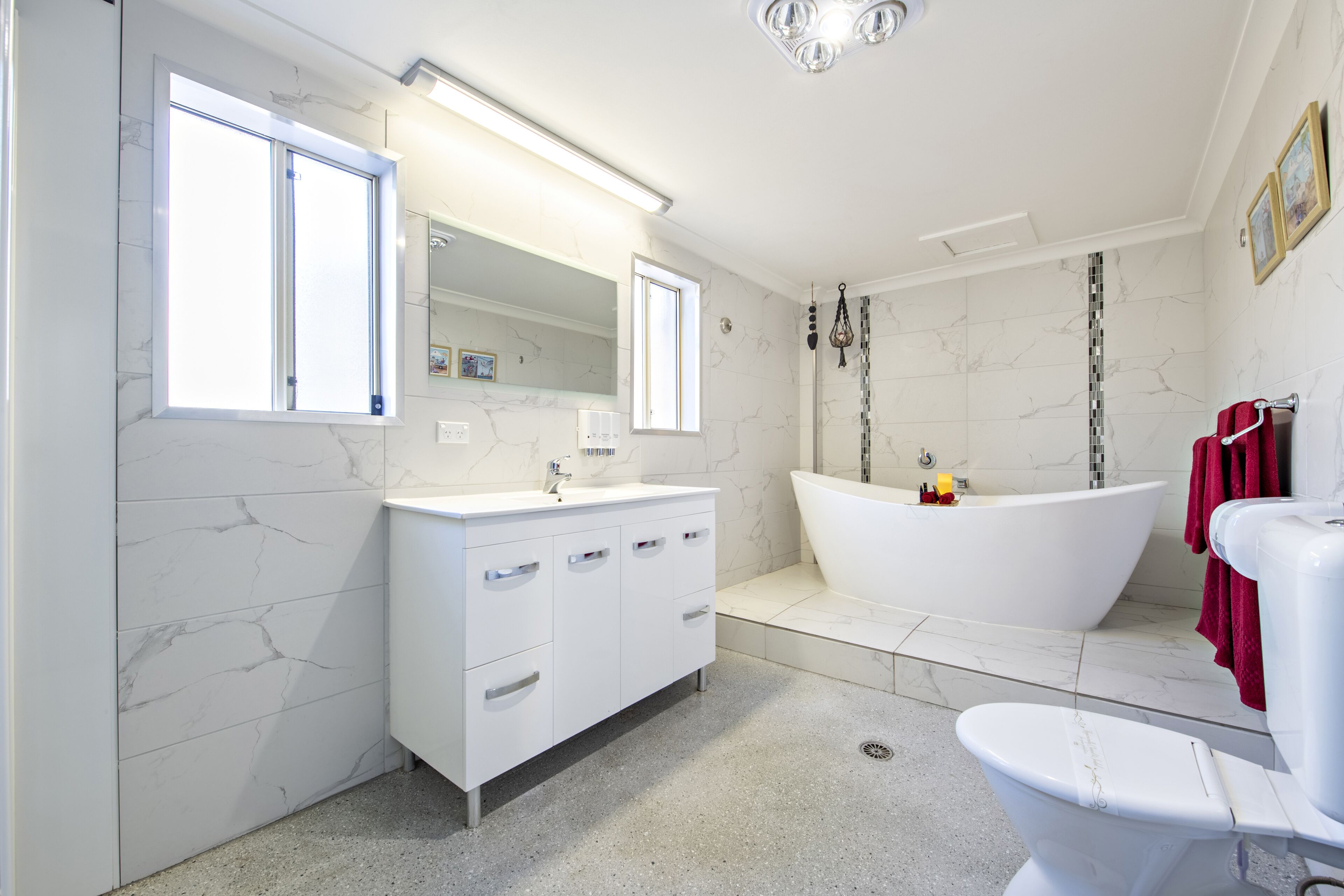 A modern bathroom with a white vanity, a freestanding bathtub, and a toilet.