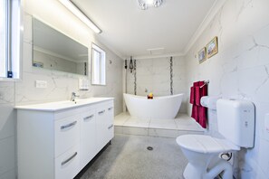 A modern bathroom with a white vanity, a freestanding bathtub, and a toilet.