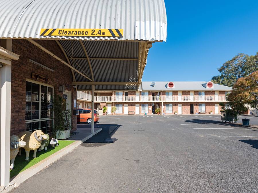 Un motel avec un panneau indiquant une voie dégagée, un parking et un bâtiment doté d’un toit en tôle ondulée.