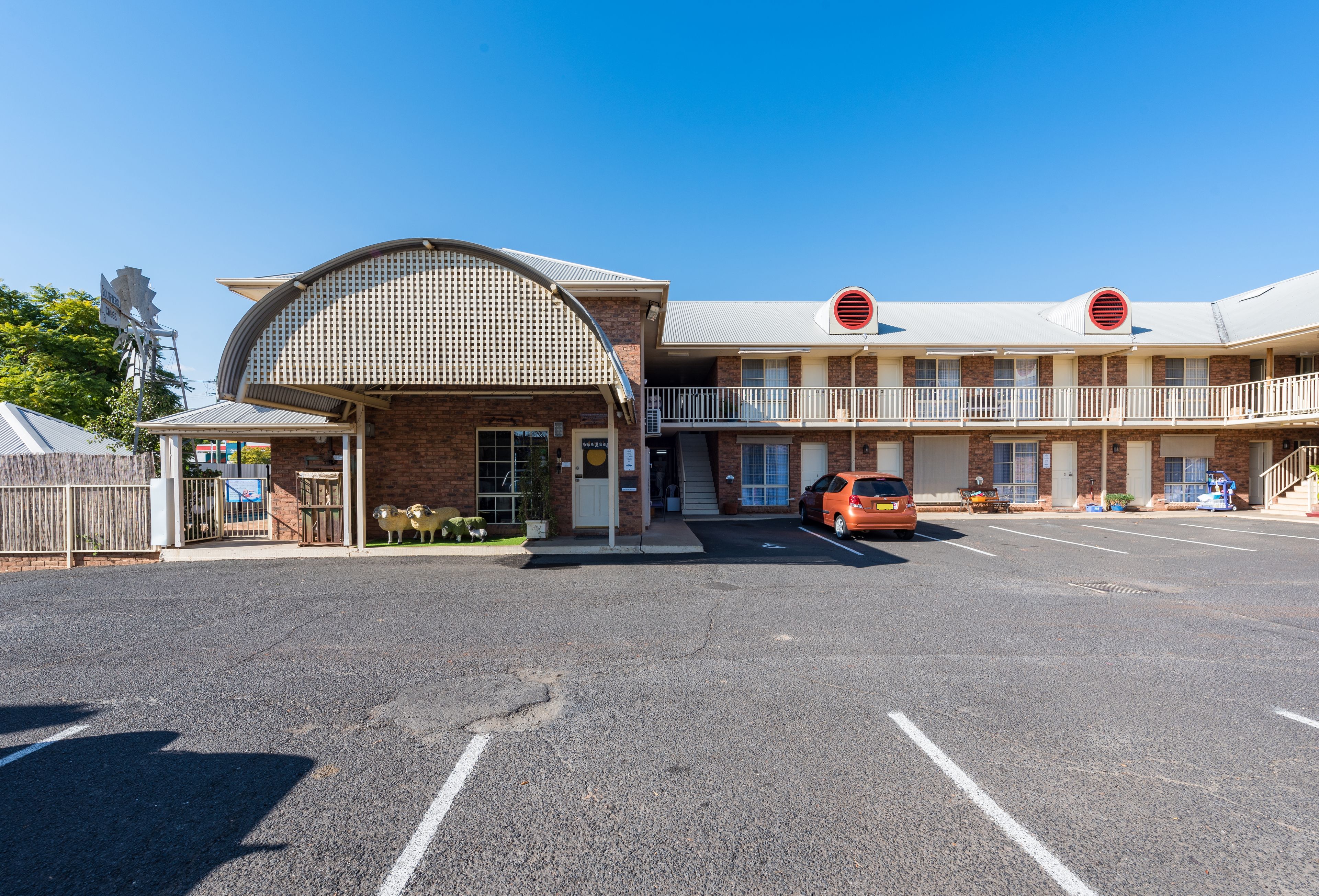 A motel with a curved entrance, multiple balconies, and a parking lot.