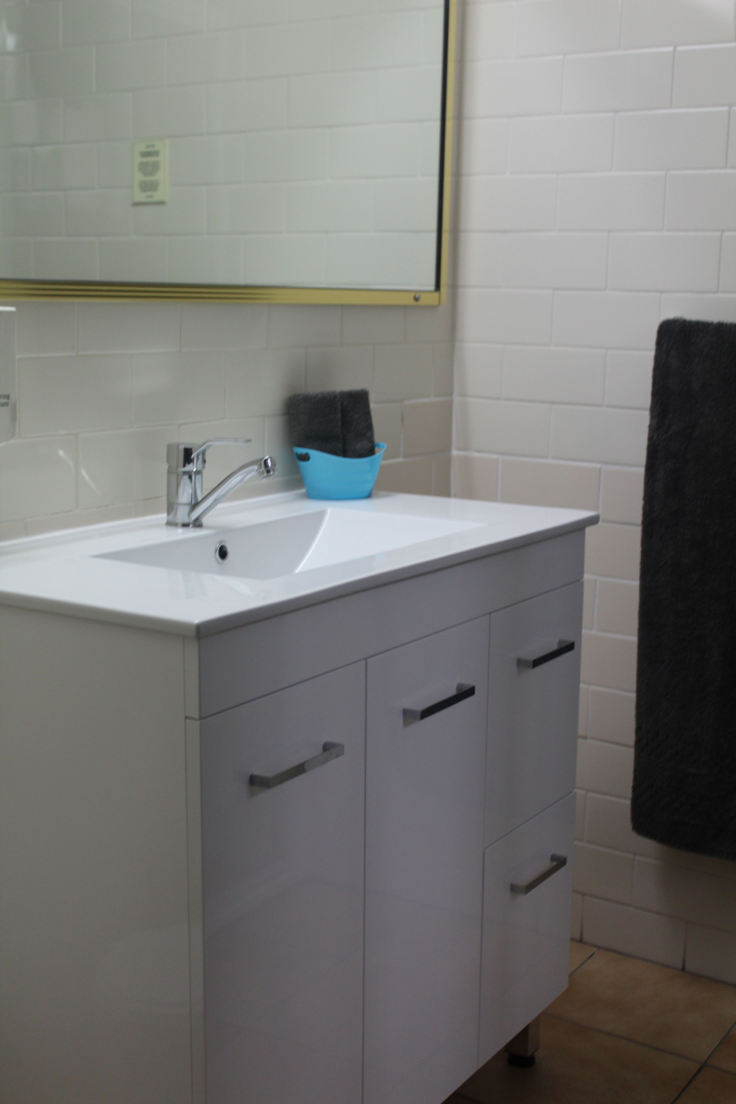 A bathroom with a white sink, a blue soap dish, and a black towel hanging on the wall.