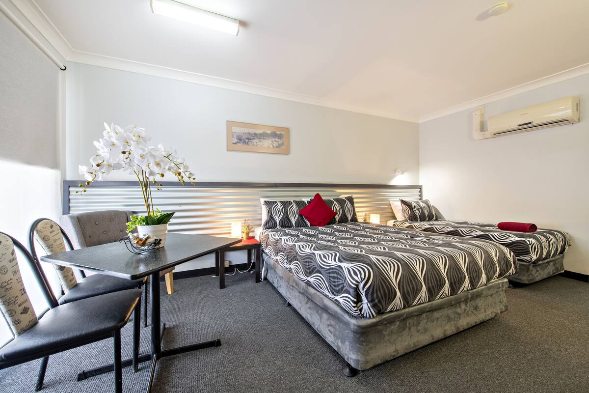 A hotel room with a bed, a desk, and chairs.