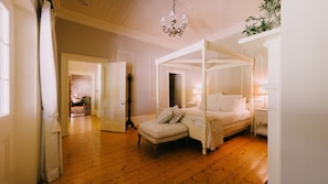 Un dormitorio con cama con dosel, una mesita de noche, una silla y suelo de madera.